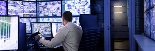 Man working in surveillance room and looking at monitors